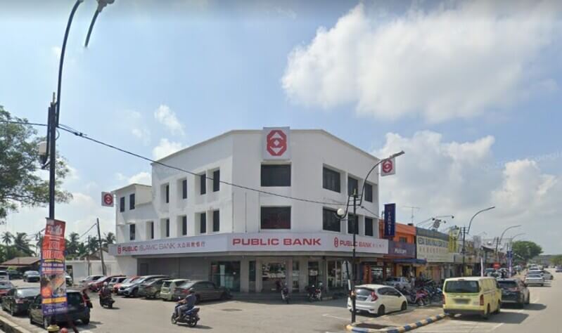 Pandangan luar bangunan cawangan Public Bank Sabak Bernam dan Public Islamic Bank bertingkat putih di tepi jalan raya dengan kenderaan diletakkan di hadapannya di bawah cuaca cerah.