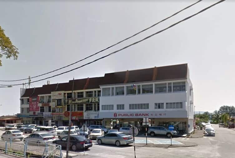 Pandangan luar cawangan Public Bank di Bagan Ajam dari sudut rendah. Bangunan putih ini menduduki sudut di antara deretan rumah kedai komersial yang pelbagai. Beberapa kereta parkir di hadapan bangunan, dan talian elektrik melintasi bahagian atas imej