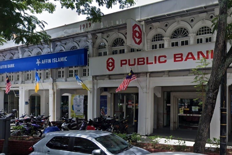 Foto paparan jalan yang menunjukkan muka depan dua bank bersebelahan dalam deretan bangunan lama gaya kolonial putih. Bank di sebelah kanan ialah Public Bank, ditandakan dengan logo dan huruf besar berwarna merah, dengan bendera Malaysia tergantung berhampiran pintu masuk. Bank di sebelah kiri ialah Affin Bank, dengan kajang biru tua dan logo bunga bergaya