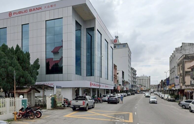 Bahagian luar bangunan Public Bank di Jalan Yang Kalsom. Bangunan moden bertingkat ini mempunyai fasad berwarna terang, mungkin logam atau berjubin, dan tingkap biru yang besar dan reflektif. Nama "PUBLIC BANK" dan aksara Cinanya "大众银行" dipaparkan dengan jelas dalam warna merah di tingkat atas dan bawah fasad bangunan