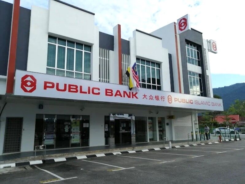 Foto bangunan komersial moden dua tingkat menempatkan pejabat Public Bank dan Public Islamic Bank di Kampar, Malaysia. Bangunan ini mempunyai fasad putih dan kelabu dengan aksen merah, tingkap besar dan tanda merah yang mencolok dengan huruf putih