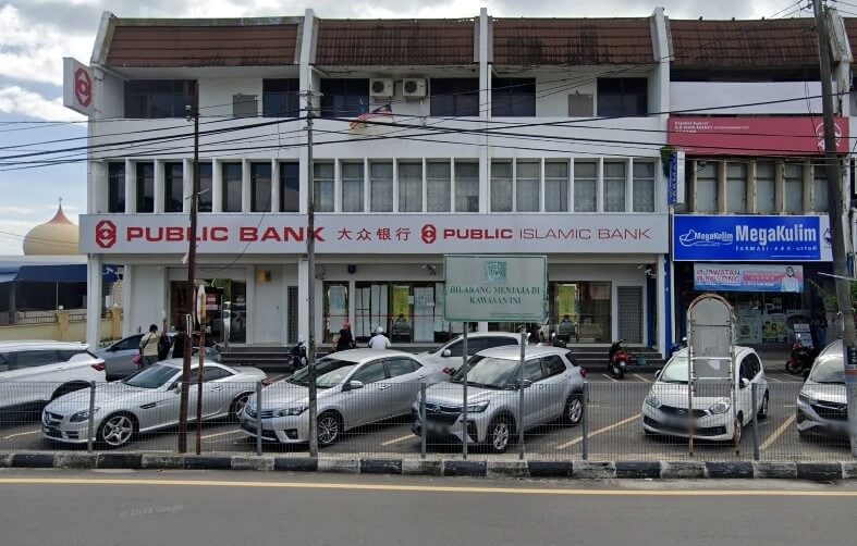 Foto bangunan tiga tingkat di Nibong Tebal, Malaysia, yang menempatkan Public Bank dan cawangan Public Islamic Bank. Bangunan putih ini mempunyai deretan tingkap berwarna gelap di tingkat dua dan papan tanda merah dan putih yang mencolok di tingkat bawah