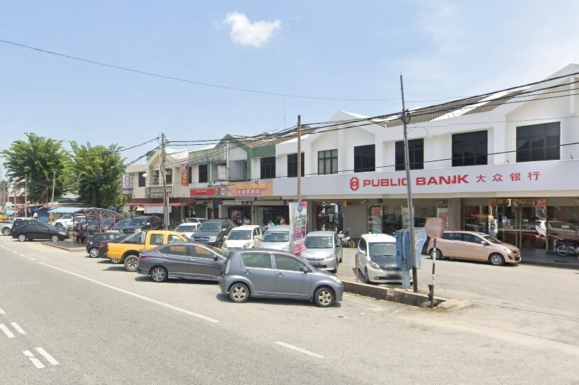 Pemandangan jalan menunjukkan deretan rumah kedai dua tingkat, dengan cawangan Public Bank Pusing yang terkenal di sebelah kanan. Jalan itu mempunyai tempat letak kereta selari bersudut di sepanjang kaki lima, dipenuhi dengan banyak kereta, termasuk hatchback kelabu, sedan gelap, trak pikap kuning dan beberapa kenderaan lain