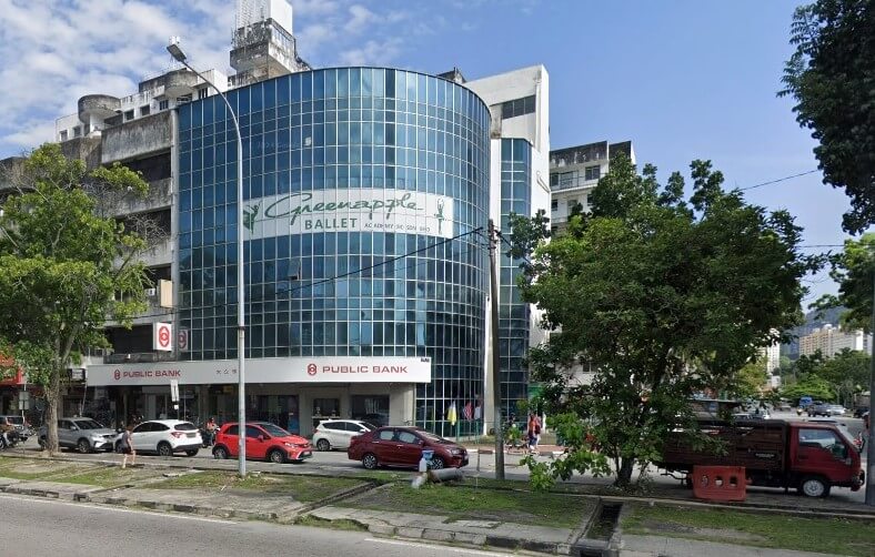 Bangunan komersial bertingkat dengan fasad kaca biru melengkung. Tingkat bawah mempunyai papan tanda "PUBLIC BANK" yang menonjol, manakala sepanduk besar di tingkat dua bertulis "Greenapple Ballet." Beberapa kereta diletakkan di sepanjang jalan di hadapan, dan pokok-pokok memenuhi kaki lima