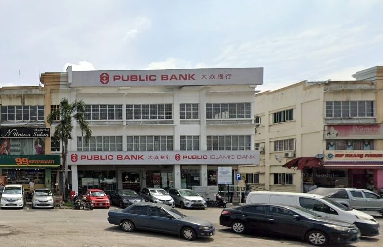 Pandangan luar cawangan Public Bank dan Public Islamic Bank di Kapar, Malaysia, sebuah bangunan putih tiga tingkat di kawasan komersial dengan kereta diletakkan di hadapan