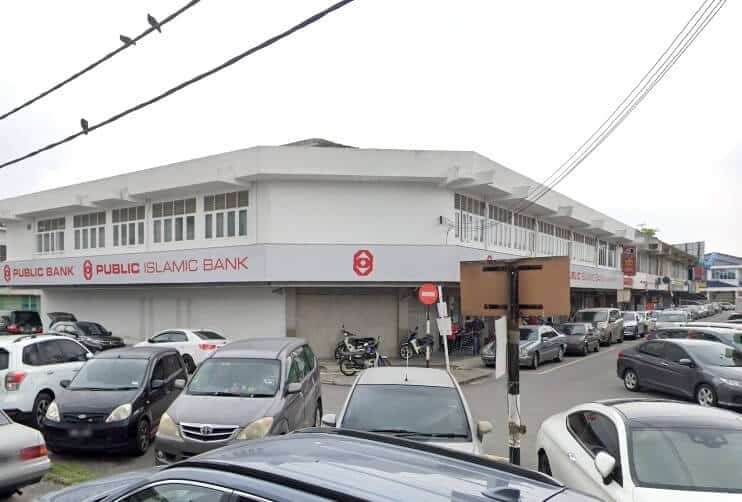 Pandangan luar cawangan Public Bank dan Public Islamic Bank dua tingkat di Taman Chi Liung, Malaysia, menunjukkan bangunan putih panjang dengan tingkap besar di tingkat atas dan papan tanda merah di tingkat bawah