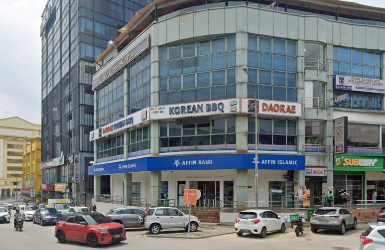 Bangunan komersial bertingkat dengan Affin Bank berwarna biru dan cawangan Affin Islamic di tingkat bawah dan restoran "Korean BBQ Daorae" di tingkat atas, terletak di kawasan bandar yang sibuk dengan kereta dan motosikal diletakkan di luar
