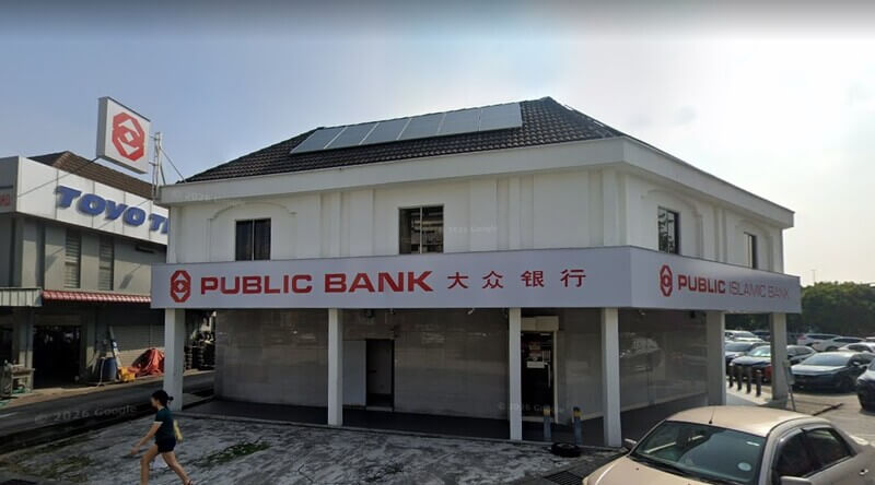 Bangunan cawangan Public Bank Subang Jaya dan Public Islamic Bank dua tingkat berwarna putih dengan papan tanda merah, panel solar di bumbung, dan laluan pejalan kaki di hadapannya.
