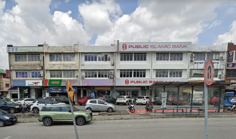 Pemandangan deretan rumah kedai tiga tingkat di tepi jalan yang menempatkan cawangan Public Bank Taman Mayang dan Public Islamic Bank, dengan kereta diletakkan di hadapannya.