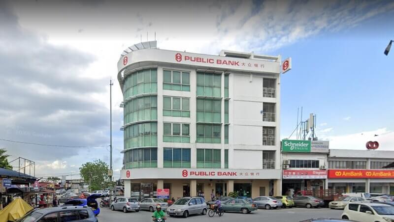 Pandangan luar bangunan cawangan Public Bank Seri Kembangan bertingkat di tepi jalan dengan kereta meletak kenderaan di hadapannya.