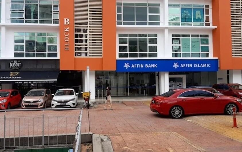 Affin Bank dan Affin Islamic, terletak di tingkat bawah bangunan komersil moden berwarna jingga dan putih berlabel "BLOK B" di Ara Damansara. Beberapa kereta, termasuk Mercedes-Benz merah, diletakkan di hadapan bangunan di kawasan berturap bata. Perniagaan lain seperti "Dugout" dan "ARA DENTAL STUDIO" boleh dilihat di tingkat atas