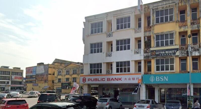 Pemandangan luar bangunan Public Bank Chukai dan BSN di deretan rumah kedai dengan kenderaan diletakkan di bahagian hadapan.