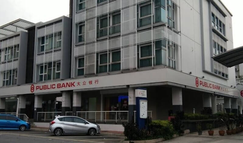 Bangunan cawangan Public Bank pelbagai tingkat dengan papan tanda "Public Bank Kota Damansara" dan beberapa buah kereta diletakkan di bahagian hadapan.