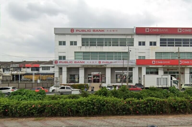 Bangunan kedai tiga tingkat berwarna putih yang menempatkan cawangan Public Bank Taman Taming Jaya di sebelah kiri serta CIMB Bank di sebelah kanan. Terdapat lorong jalan raya, pokok renek, dan beberapa kenderaan diletakkan di bahagian hadapan bangunan.