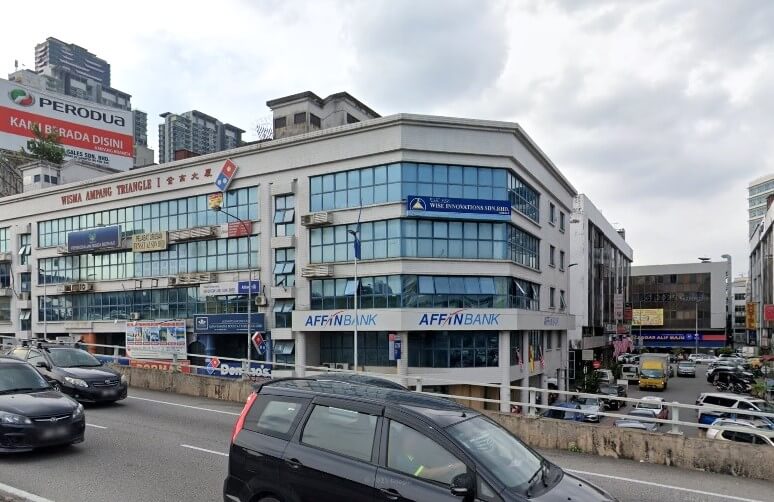 Gambar jalan cawanganAffin Bank Ampang Jaya dan perniagaan lain di tingkat bawah bangunan komersil bertingkat Wisma Ampang Triangle di Malaysia, dengan sebuah kereta hitam melalui di latar depan