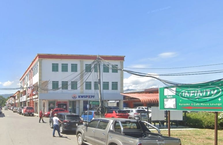 Bangunan komersial tiga tingkat putih dan merah dengan logo "KWSP/EPF" biru di tingkat bawah, boleh dilihat dari jalan. Papan tanda berwarna hijau dengan tulisan "Infinity Karaoke & Cafe House Lounge" kelihatan di sebelah kanan