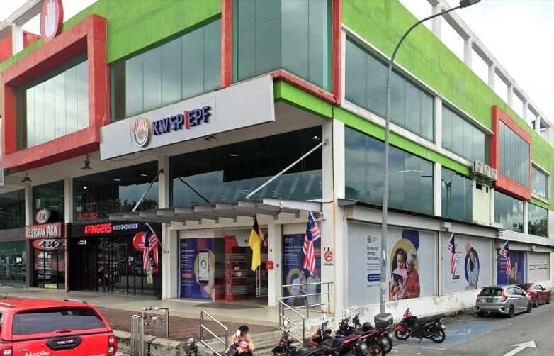 Bahagian luar pejabat cawangan KWSP Nilai di Negeri Sembilan, sebuah bangunan tiga tingkat dengan fasad berwarna merah dan hijau, terletak di atas kawasan komersial di tingkat bawah, termasuk Restoran A&W dan kedai 4Fingers Crispy Chicken