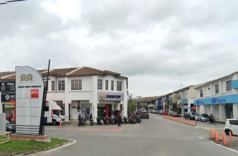 KWSP Parit Buntar di Perak, Malaysia. Bangunan sudut dua tingkat berwarna putih ini ditanda dengan perkataan "KWSP EPF" yang menarik dengan warna merah dan kuning. Beberapa buah motosikal diparkir berhampiran pintu masuk. Jalan tersebut terbentang ke kanan dengan deretan rumah kedai lain termasuk cawangan RHB Bank