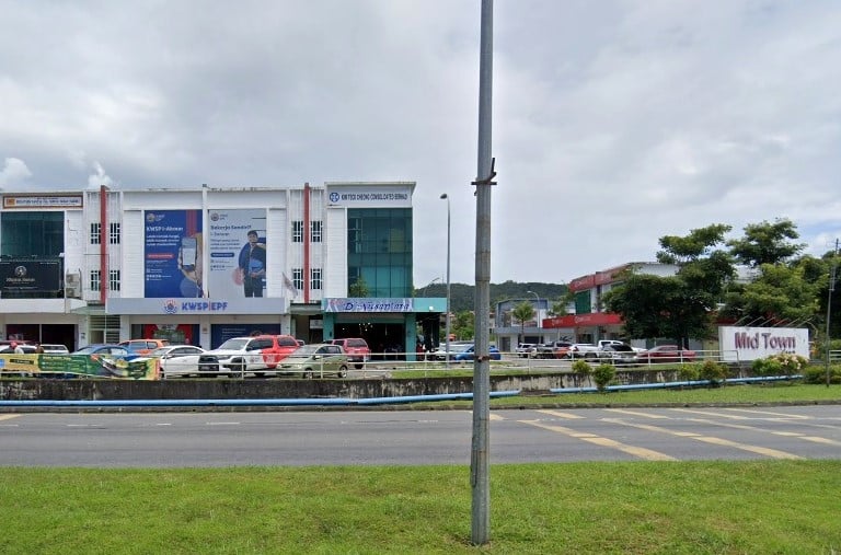 Kompleks bangunan komersial tiga tingkat. Bangunan di bahagian tengah mempunyai papan tanda berwarna biru dan putih untuk KWSP/EPF (Employees Provident Fund) Sandakan. Di hadapan bangunan itu terdapat kawasan parkir, dipisahkan dari jalan utama oleh penghadang biru. Papan tanda yang menyatakan Mid Town kelihatan di hujung kanan