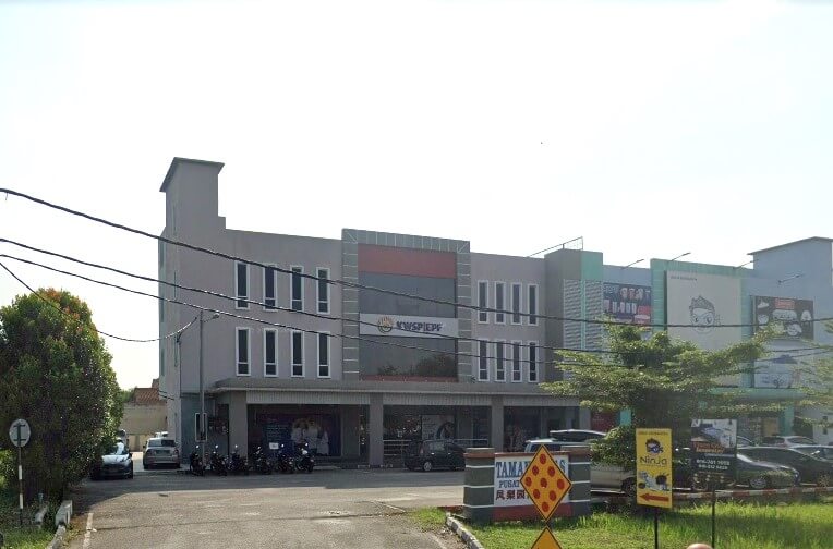 Pemandangan luar bangunan pejabat KWSP Teluk Intan di Perak, Malaysia. Bangunan komersial tiga tingkat dengan papan tanda 'KWSP/EPF' yang menonjol di tingkat atas, dikelilingi kawasan parkir berturap dan muka hadapan kedai lain