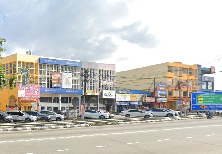 Deretan rumah kedai berwarna-warni memenuhi jalan yang sibuk, dengan pejabat Affin Bank dan Affin Islamic terletak di dalam bangunan putih dan biru di tengah-tengah