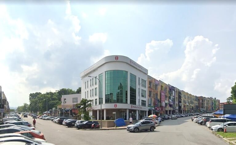 Pemandangan jalan di luar bangunan cawangan Public Bank Bandar Mahkota Cheras, Selangor, Malaysia. Bangunan putih dan kaca melengkung yang tersendiri, dikelilingi deretan rumah kedai yang berwarna-warni dan jalan yang sibuk dengan kereta yang diletakkan
