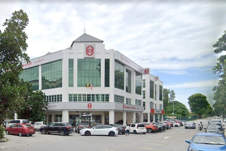 Sebuah bangunan komersial yang besar, moden, putih, bertingkat dengan menara di tengah, menempatkan cawangan Public Bank Bandar Puteri Puchong yang terkenal dengan papan tanda merah