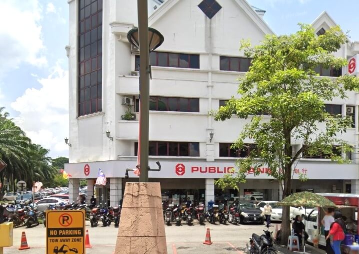 Sebuah bangunan putih empat tingkat yang merupakan pejabat cawangan Public Bank Bandar Sunway, dengan bumbung gable yang tersendiri. Bahagian hadapan mempunyai kawasan parkir yang sibuk, kebanyakannya dipenuhi dengan motosikal, tiang lampu dengan tapak batu, dan papan tanda 'Dilarang Parkir dan Menunda'.