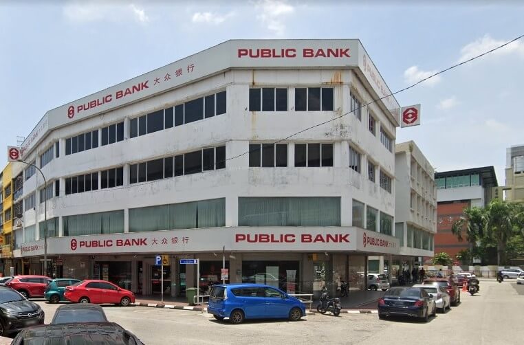 Bahagian luar cawangan Public Bank empat tingkat yang besar di Jalan Tapah menampilkan bangunan putih yang menarik dengan banyak tingkap dan papan tanda merah tebal dalam bahasa Inggeris dan Mandarin