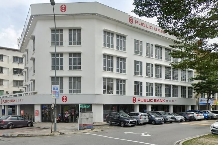Sebuah bangunan putih empat tingkat dengan banyak tingkap di satu sudut, menampilkan logo "Public Bank" dan nama berwarna merah di muka depan tingkat atas dan bawah