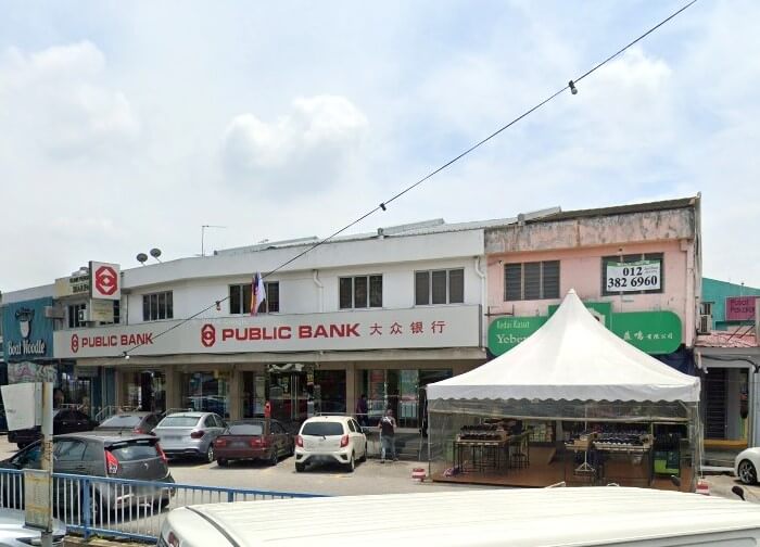 Bahagian luar cawangan Public Bank berwarna putih dua tingkat, terletak di tengah-tengah deretan bangunan komersial, namanya ditulis dalam aksara Inggeris dan Cina merah yang boleh dilihat di tingkat bawah