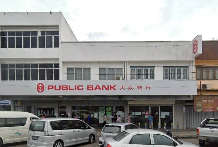 Bahagian luar cawangan Public Bank Sungai Jarom, menampilkan bangunan putih dua tingkat dengan beberapa tingkap segi empat tepat dan papan tanda merah yang mencolok dalam bahasa Inggeris dan Mandarin