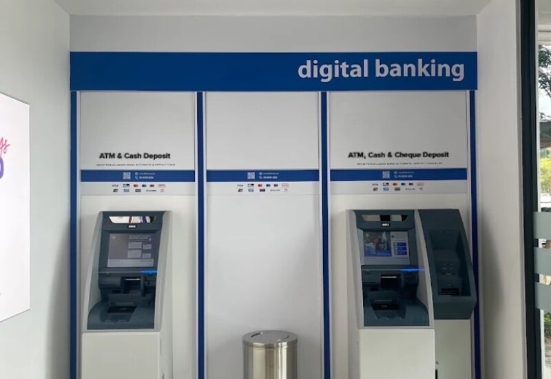 Bahagian dalam kios perbankan digital Affin Bank Bandar Sri Indah yang menampilkan dua mesin juruwang automatik (ATM) untuk deposit tunai dan cek, diletakkan pada dinding putih dan biru bersih dengan tong perak tengah