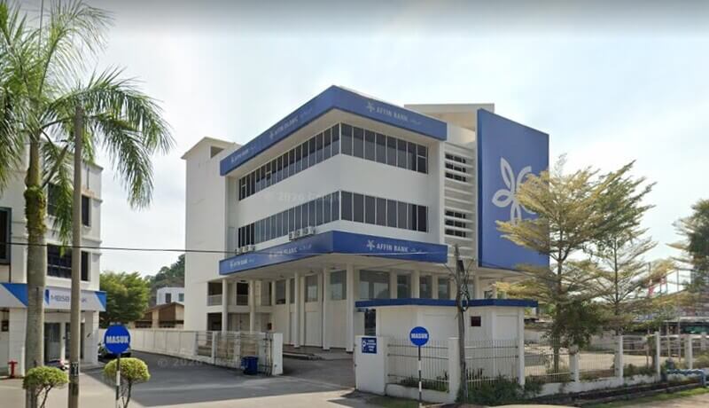 Pemandangan dari jalan jalan raya yang cerah menunjukkan bangunan cawangan Affin Bank Kemaman dan Affin Islamic di Malaysia, dengan bangunan MBSB Bank yang berdekatan dan pokok-pokok palma.