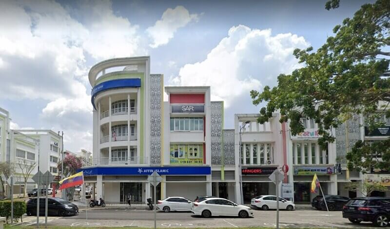 Pemandangan hadapan barisan bangunan kedai moden empat tingkat di kawasan bandar pada hari cerah, menampilkan cawangan cawangan Affin Bank Presint 15 di tingkat bawah pada unit sudut (corner lot). Bangunan ini mempunyai seni bina putih moden dengan panel hiasan berkerawang, papan tanda biru Affin Islamic