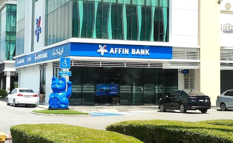 Bangunan cawangan Affin Bank Saradise di kawasan komersial dengan patung kucing biru Maneki-neko di hadapan pintu masuk.