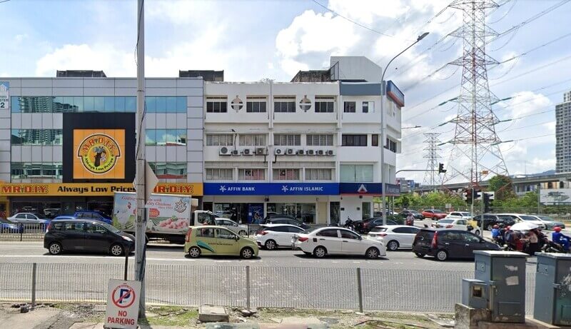 Pemandangan aras jalan bagi bangunan komersial berwarna putih dengan cawangan Affin Bank dan Affin Islamic di tingkat bawah, terletak bersebelahan MR. D.I.Y. store. Latar depan menunjukkan lalu lintas padat di jalan berbilang lorong, dengan tiang elektrik tinggi kelihatan di latar belakang