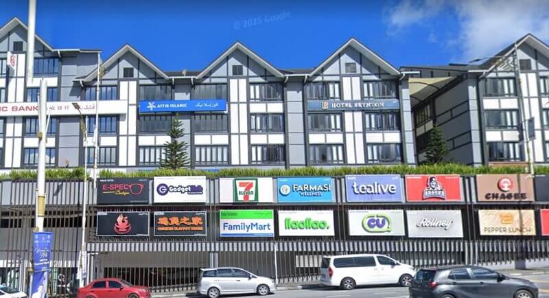 Pandangan luar bangunan komersial bergaya senibina Tudor di Cameron Highlands yang menempatkan cawangan Affin Bank Cameron Highlands, Hotel Brinton, serta deretan papan tanda kedai seperti 7-Eleven, Tealive, dan FamilyMart