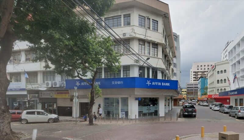 Pandangan luar premis cawangan Affin Bank Jalan Gaya yang terletak di sudut bangunan kedai berbilang tingkat di kawasan bandar, menampilkan papan tanda biru bertulis "AFFIN BANK" dan logo perbankan.