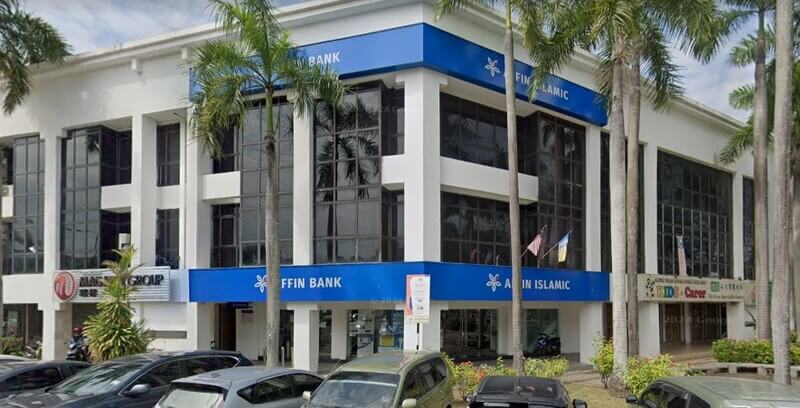 Pandangan hadapan bangunan cawangan AFFIN Bank prai dan AFFIN ISLAMIC tiga tingkat bernuansa putih dan biru dengan beberapa pokok kelapa sawit di hadapannya serta kereta diparkir di bahagian luar.