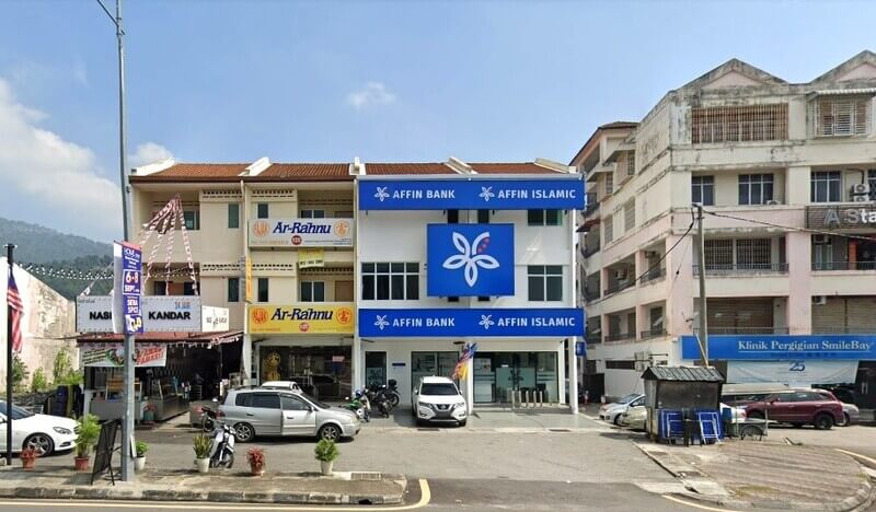 Pandangan luar cawangan Affin Bank dan Affin Islamic tiga tingkat di Air Itam, menampilkan papan tanda biru dan putih, terletak di antara cawangan Ar-Rahnu dan klinik pergigian dengan tempat letak kereta di hadapan