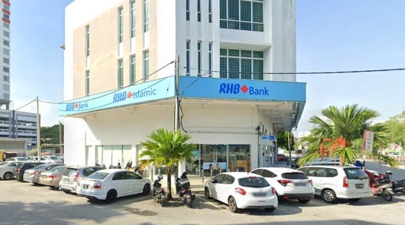 Pemandangan luar cawangan RHB Bank di Bukit Mertajam dan RHB Islamic yang terletak di sebuah bangunan putih berbilang tingkat, dengan beberapa buah kereta diparkir di hadapannya.