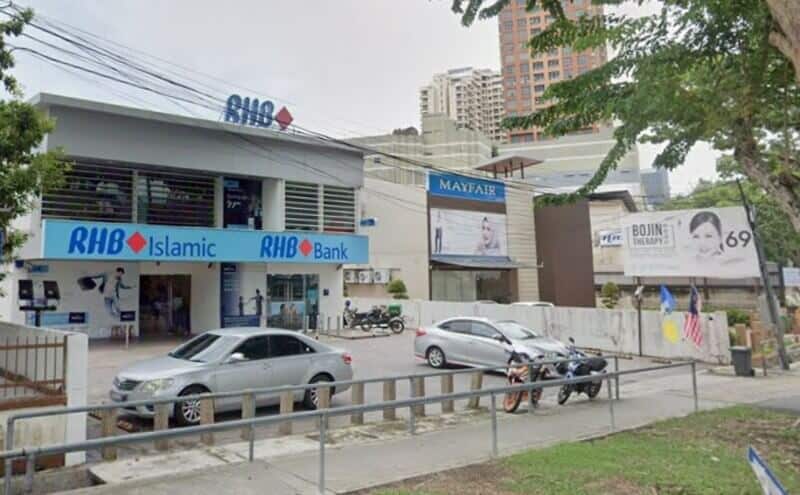 Pandangan luar Bank RHB dan cawangan RHB Islamic di Jalan Burma, menampilkan bangunan dua tingkat berwarna putih dengan papan tanda biru dan ruang letak kereta kecil di hadapan