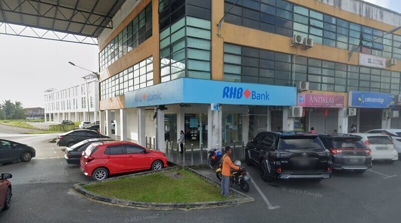 andangan luar RHB Bank Mukah dan cawangan RHB Islamic berwarna biru yang terletak di sudut jalan di Mukah, menampilkan bangunan tiga tingkat dengan kereta yang diletakkan di hadapan