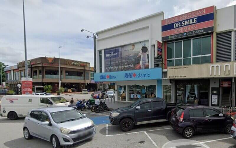 Pandangan luar jalan komersial yang menampilkan cawangan RHB Bank dan RHB Islamic, yang terletak bersebelahan Klinik Pergigian Dr. Smile di Seremban 2, dengan kereta diletakkan di hadapan