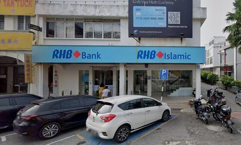 Bahagian luar Bank RHB dan cawangan RHB Islamic di Seremban, memaparkan papan tanda kedai berwarna biru muda, sebuah kereta putih yang diletakkan di hadapan dan papan iklan kad RHB Visa Multi Currency yang besar di tingkat atas