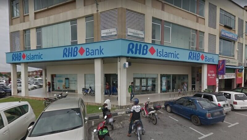 Pandangan luar cawangan RHB Bank dan RHB Islamic di Unisquare, Kota Samarahan, yang menampilkan papan tanda biru pada bangunan komersial bertingkat dengan tempat letak kereta aras jalan