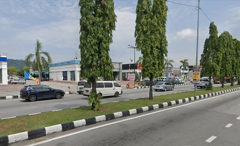Pandangan luar cawangan RHB Bank di Auto City dari tepi jalan raya yang dikelilingi pokok-pokok dan kenderaan