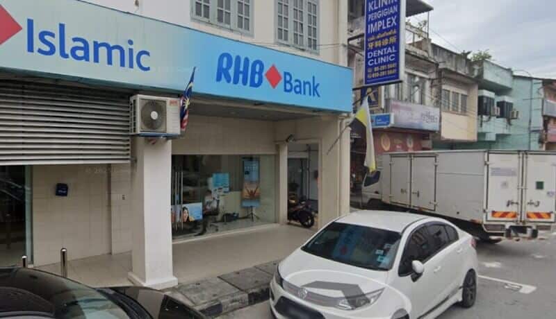 Pandangan luar cawangan RHB Bank dan RHB Islamic di Menglembu, memaparkan papan tanda biru pada bangunan lot kedai putih dengan tempat letak kereta di tepi jalan