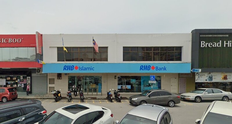 Pandangan hadapan cawangan RHB Bank Jalan Raja Uda dan RHB Islamic dua tingkat dengan beberapa kenderaan diletakkan di tempat letak kereta di hadapan kedai